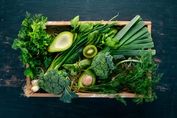 Fotobehang Fresh green vegetables and fruits in a wooden basket. Healthy food. Top view. Copy space. © Yaruniv-Studio