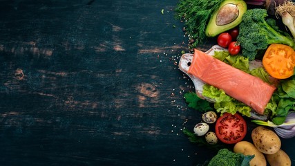 Salmon fillet and fresh vegetables. Healthy food. On a black wooden background. Healthy food. Top...
