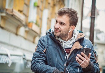Young handsome man using smartphone and listening music