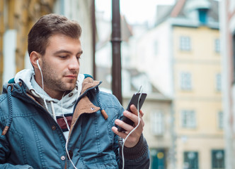 Young man with cell phone and earphones listening music - obrazy, fototapety, plakaty