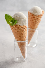 Vanilla ice cream in waffle cone on gray concrete background, selective focus