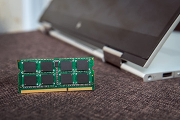Memory card RAM for laptop on the background of a laptop-transformer folded into a tablet. DDR for...