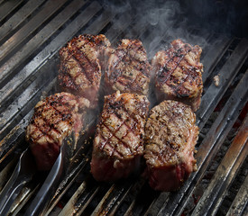 Steaks with spices on hot grill. Food background.