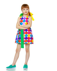 A little girl in a dress with a pattern from multi-colored circl