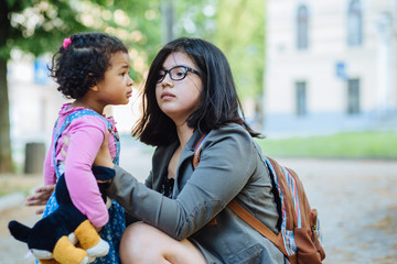 Outdoor close up portrait of young ecuadorian mother and mixed race dark skinned toddler daughter...