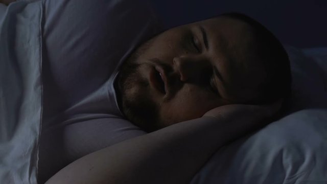 Chubby male snoring at night in bed, sleeping apnea caused by excess body weight