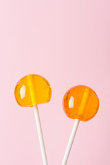 Lollipops on white plastic sticks on pink pastel background vertical with copy space