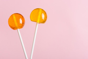 Lollipops on white plastic sticks on pink pastel background with copy space