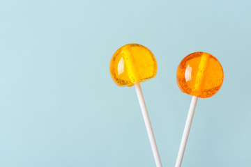 Two big bright tasty lollipops on white sticks on blue pastel background with copy space