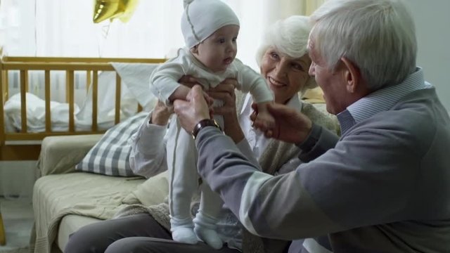 Tilt up of happy grandparents playing with adorable baby boy