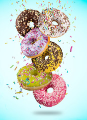 Tasty doughnuts in motion falling on pastel blue background.