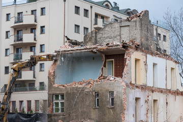 Residential building demolition with excavator