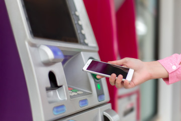 Woman holding a Smartphone financial transactions online on the background, ATM cabinet. Online NFC...