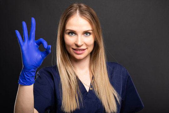 Beautiful female dentist wearing scrubs showing ok gesture.