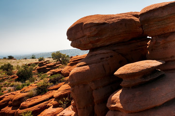 A group of fantastically nature shaped yellow red rocks in the South African Magaliesberg plateau on a sunny day with blue sky and hills in the background