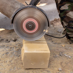 A man cuts a brick at a construction site