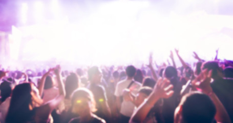 blurry of silhouettes of concert crowd at Rear view of festival crowd raising their hands on bright...