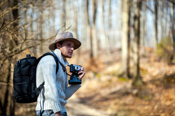 Traveler man with vintage camera and backpack, hipster tourist in forest