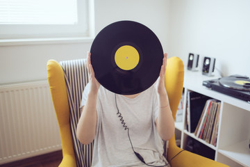 Audiophile holding vinyl record in front of head