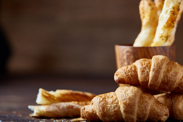 Delicious breadsticks grissini on wooden dark background in wooden oldstyle cup, close-up, selective focus