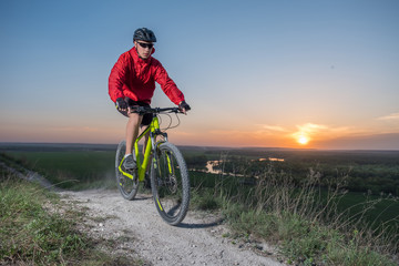 A cyclist in a red jacket rides a bike along the mountain path. The concept of extreme sports. Mountain bike.