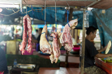 Homemade Thai traditional food concept, sun dried beef and pork hang on bamboo with blurred view thai country market background in afternoon time.