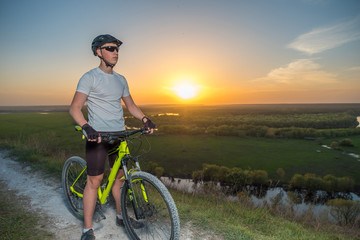 A cyclist in a white T-shirt rides a bike along the mountain path. The concept of extreme sports. Mountain bike.