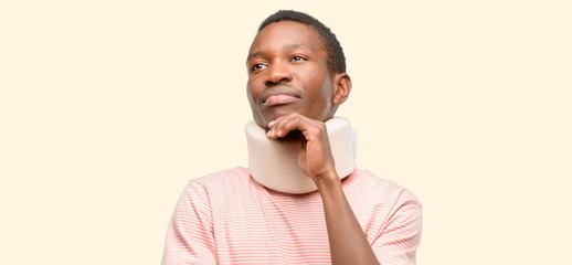 Injured african black man wearing neck brace thinking and looking up expressing doubt and wonder