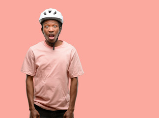 Black man wearing bike helmet scared in shock, expressing panic and fear
