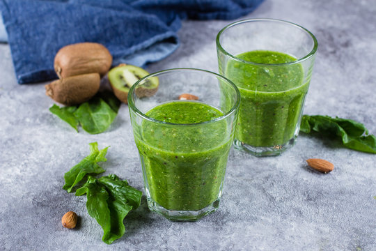 Helathy Green Smoothie with green apple, spinach, kiwi and almond nuts on gray concrete background. Food and drink, healthy lifestyle, diet and nutrition concept.