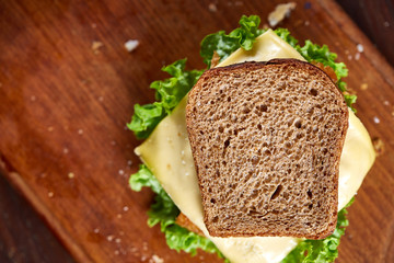 Tasty and fresh sandwiches on cutting board over a dark wooden background, close-up