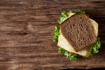 Tasty and fresh sandwiches on cutting board over a dark wooden background, close-up