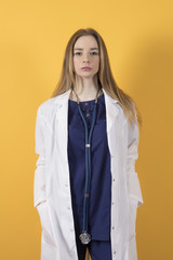 European doctor in a surgical suit and a white coat on a yellow background