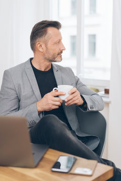 Attractive trendy man relaxing with coffee at home