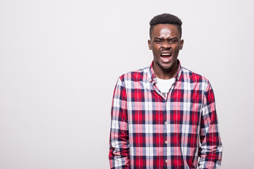 Fototapeta premium Emotional screaming young african man standing isolated over white background.