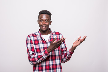 Portrait with empty place afro american man with beaming smile pointing two forefingers to copy space, looking at camera, isolated on grey background