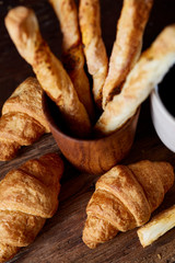 Puff pastries on piece of board over dark wooden table, close-up, selective focus, backlight.