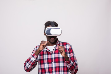 young happy and excited afro american man wearing virtual reality vr goggles enjoying video game isolated on white background in innovation and gaming box