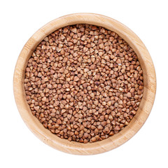 Roasted brown buckwheat grains in wooden bowl isolated on white. Top view.