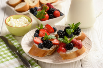 Healthy breakfast fruits and ricotta sandwiches- with strawberries, blueberries and blackberries.
