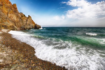 Sea waves crashing on the shore and flowing above seashore pebbles