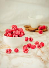 Raw raspberries and wild black, blackberries in white cups. Light marble background. Summer fruit, berries. Detox diets and healthy food concept.