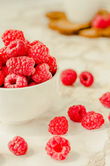Raw raspberries and wild black, blackberries in white cups. Light marble background. Summer fruit, berries. Detox diets and healthy food concept.