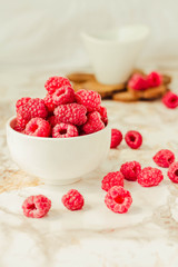 Raw raspberries and wild black, blackberries in white cups. Light marble background. Summer fruit, berries. Detox diets and healthy food concept.