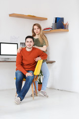 People and family concept.Portrait of young startup couple wear bright clothes, pose together against white background with desk at home. Man and woman have happy expressions and truthful relationship