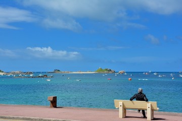 Un homme assis sur un banc face à la mer à Penvénan Port-Blanc en Bretagne