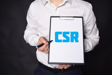 In the hands of a businessman a notebook with the inscription:CSR