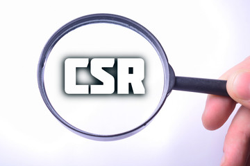 Businessman looking at a magnifying glass word:CSR