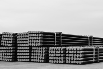 Rows of Steel Pipes storage and stacking outside warehouse for industrial construction in Black and white.
