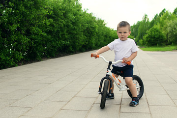 Little boy on a bicycle. Caught in motion, on a driveway. Preschool child's first day on the bike. The joy of movement. Little athlete learns to keep balance while riding a bicycle.